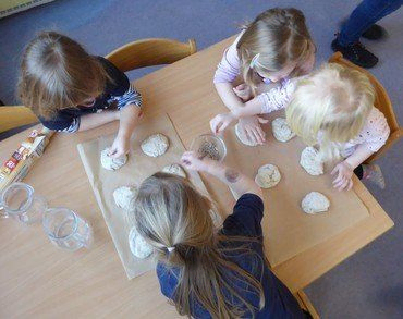 Vier Kinder dekorieren Teig an einem Tisch.